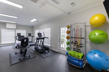 A gym room with a variety of equipment including a treadmill, exercise ball, and resistance bands.